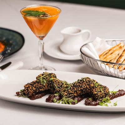 Sesame-crusted feta with dried figs and honey, served with a cocktail and pita bread.