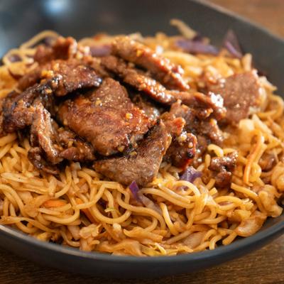 Steak Yakisoba featuring stir-fried noodles topped with sliced steak.