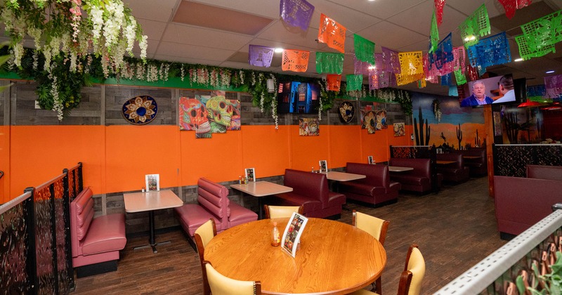 Festive restaurant interior with vibrant wall art, and cozy red booths