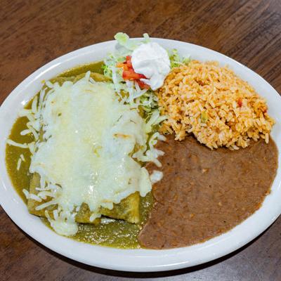 Green enchiladas with melted cheese served with rice, beans, and lettuce.