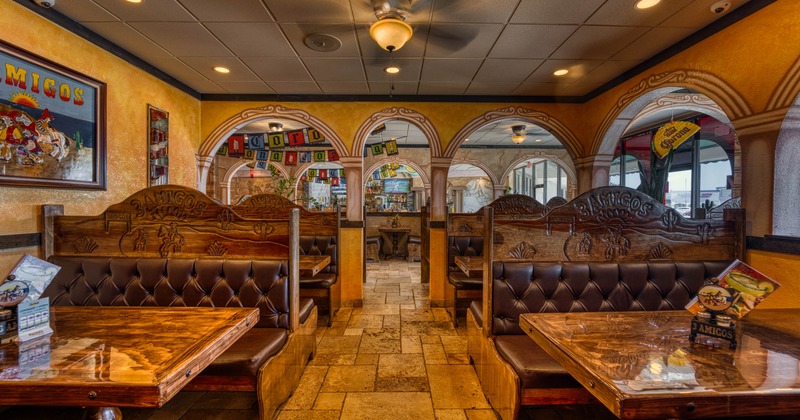 Interior of a restaurant with brown leather booths, wooden tables, and colorful banners overhead