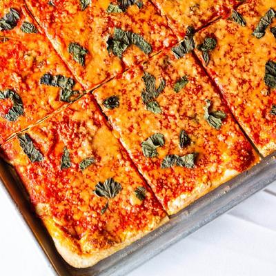 Square Pizza topped with tomato sauce and herbs.