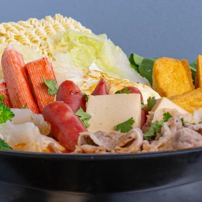 Tomato soup bowl with broccoli, tofu, crab sticks and sliced meat.