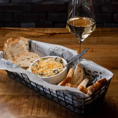 Spinach and cheese dip, bread, and a glass of white wine.
