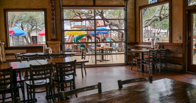Interior with wooden furniture and a view of a colorful outdoor playground through large windows