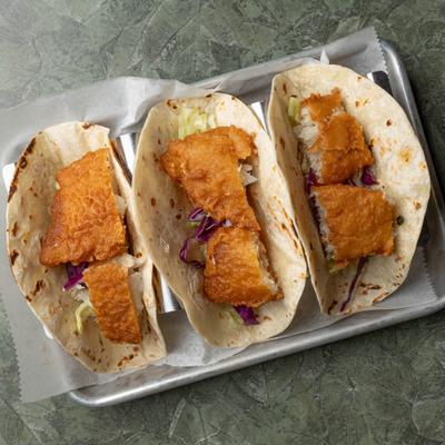 Three fish tacos served on a plate.