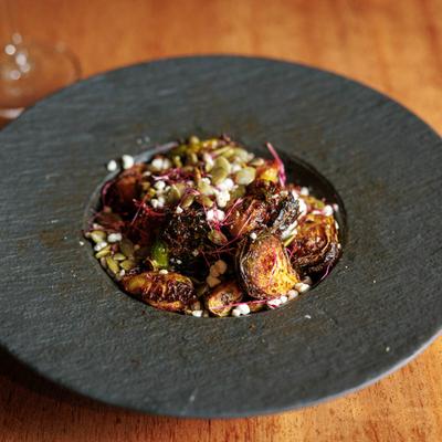 Crispy brussels sprouts with seeds and microgreens in an elegant black plate