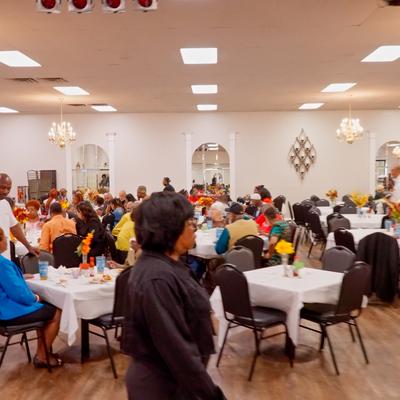 Venue's main room with people seating at the tables.