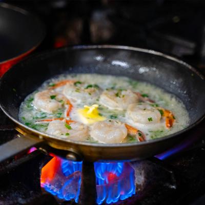 Shrimp being cooked in a pan over a gas flame.
