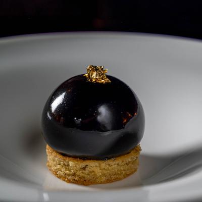 Spherical chocolate dessert, on top of an almond cake.