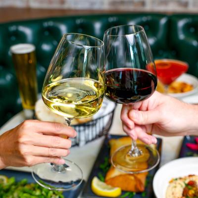 hands holding a glass of wine wine and a glass of red wining cheersing.