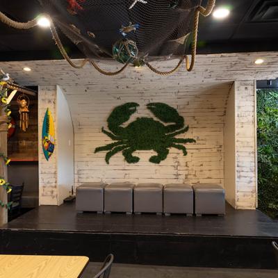 An area with netted ceiling decor, a green crab wall art, and gray seating.