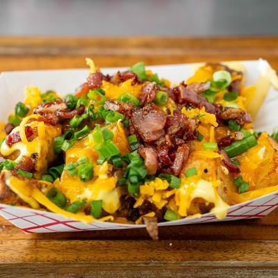 Fried potatoes with cheese, chives, bacon, and sauce.