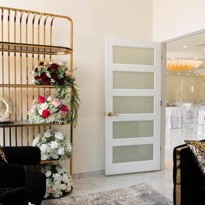 Room with furniture, floral arrangements and doorway leading into event hall.