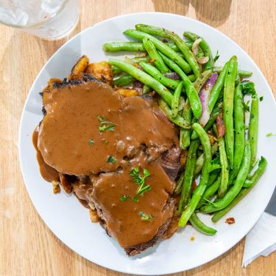 Roasted beef topped with gravy, served with green beans.