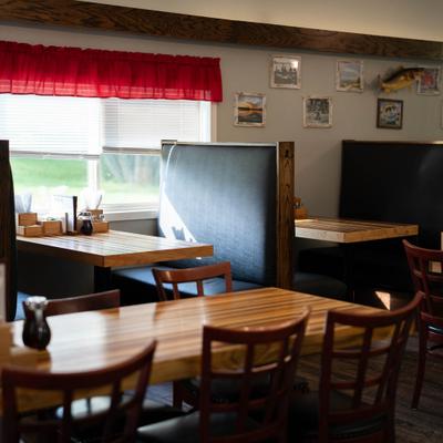 Casual restaurant interior featuring booth seating, wooden tables, and framed art.
