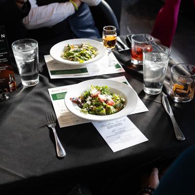 Fresh salads served at a dining table with drinks and event menus.