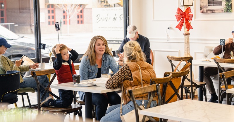 Guests enjoying food and drinks in a a bright cafe with large windows