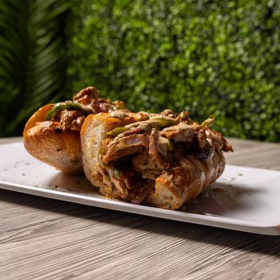 A sandwich loaded with savory fillings and drizzled with sauce.