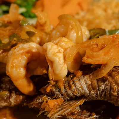 Red snapper topped with shrimp, served with sides, close-up.