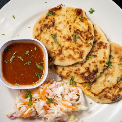 Pupusas served with red tomato salsa and a side of pickled cabbage slaw.