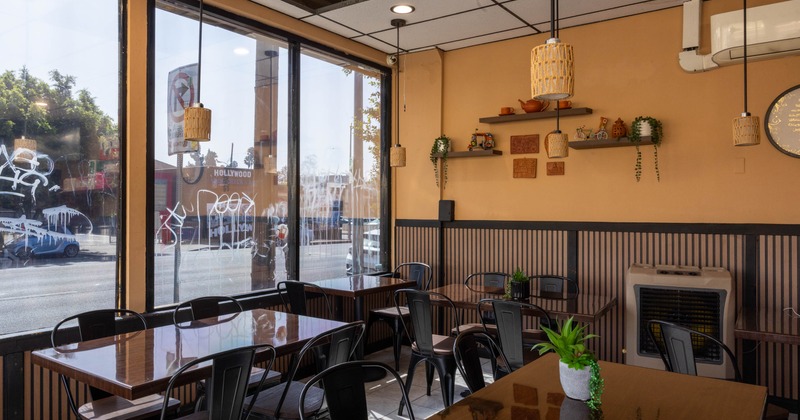 Interior of a cafe with wooden tables, black chairs, and decorative shelves