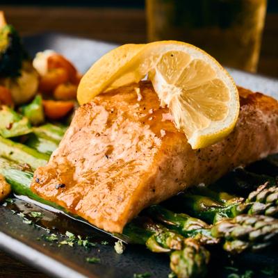 Grilled salmon served over asparagus with a slice of lemon on top.