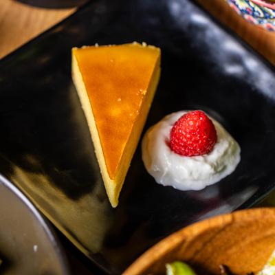 Yuzu cheesecake slice with whipped cream and strawberry garnish.