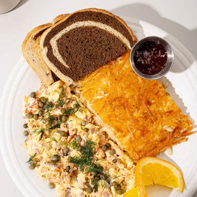 Smoked Salmon Scramble, hashbrowns, rye toast, cup of jam, and orange slice.
