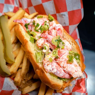 Lobster roll served with fries and pickle spears.