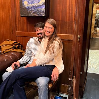 Two people sitting closely on a leather chair in a warmly-lit room.