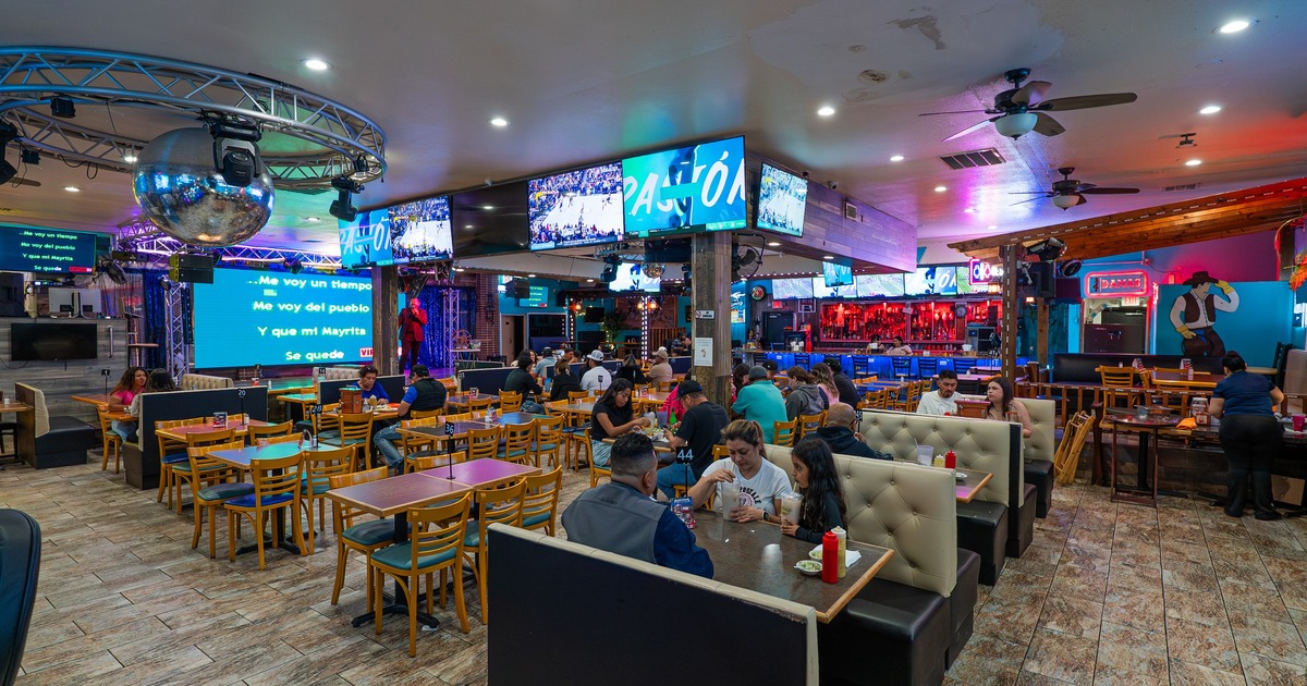 Interior with table and booth seating, stage area and numerous televisions