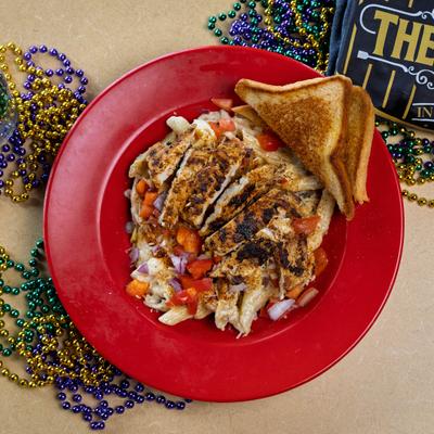 Pasta dish topped with grilled chicken and served with toasted bread.