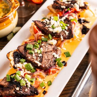 Beef tenderloin bruschetta, with cheese, tomatoes, onion, and balsamic reduction.