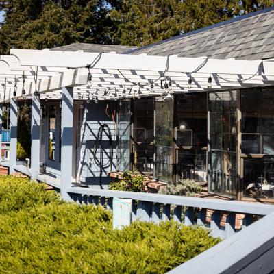 Restaurant exterior with patio seating and greenery.