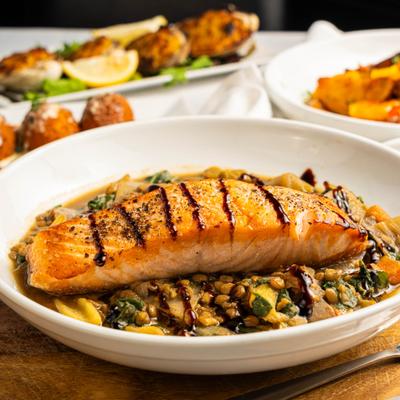 Pan seared market salmon over braised umbrian lentils with vegetables.