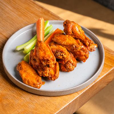 Serving of chicken wings with carrot and celery sticks on the side.
