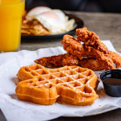 Chicken and waffles served with syrup.