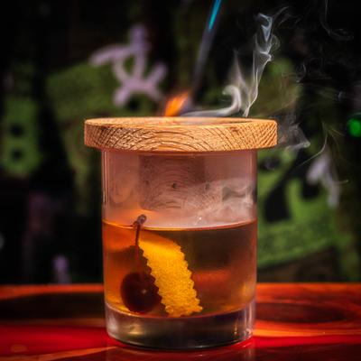 Smoked Rum Old Fashioned, garnished with orange peel and candied cherries