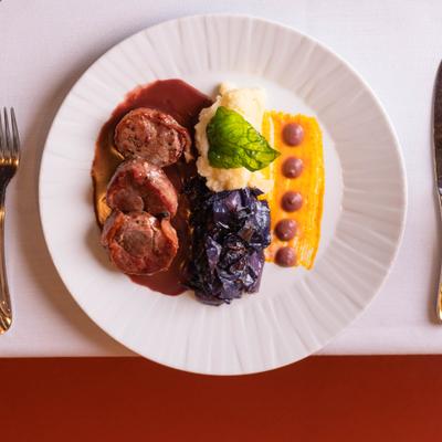 Pancetta wrapped pork tenderloin with mashed potatoes and vegetables.