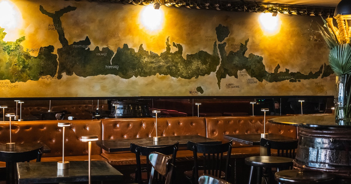 Interior of upscale lounge seating area with dark wooden tables and tufted leather booth seating