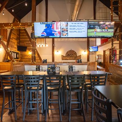 Interior with high top table with stools, wooden booths and multiple TV screens.