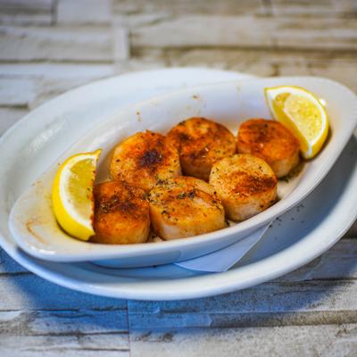 Grilled scallops with garlic butter and lemon wedges.