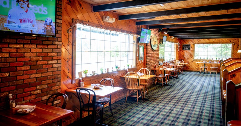 Interior, wooden paneling, brick walls, tables, chairs, large windows, and a television