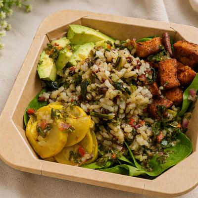 Grain bowl with roasted veggies, greens, avocado, and herbs.