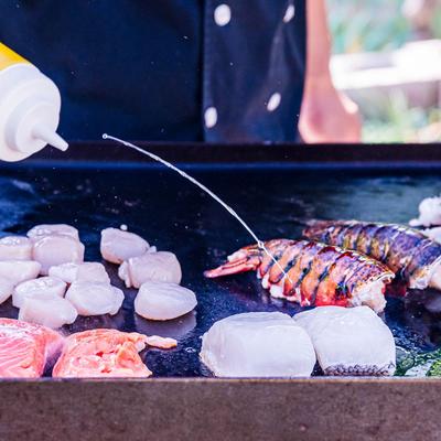 Chef cooking seafood on an outdoor grill.