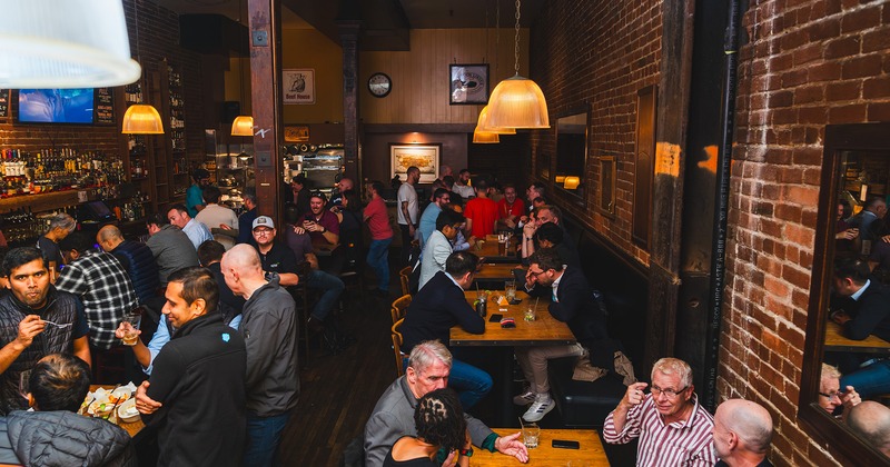 Interior space, bar and seating area full of guests chatting and enjoying their food and drinks