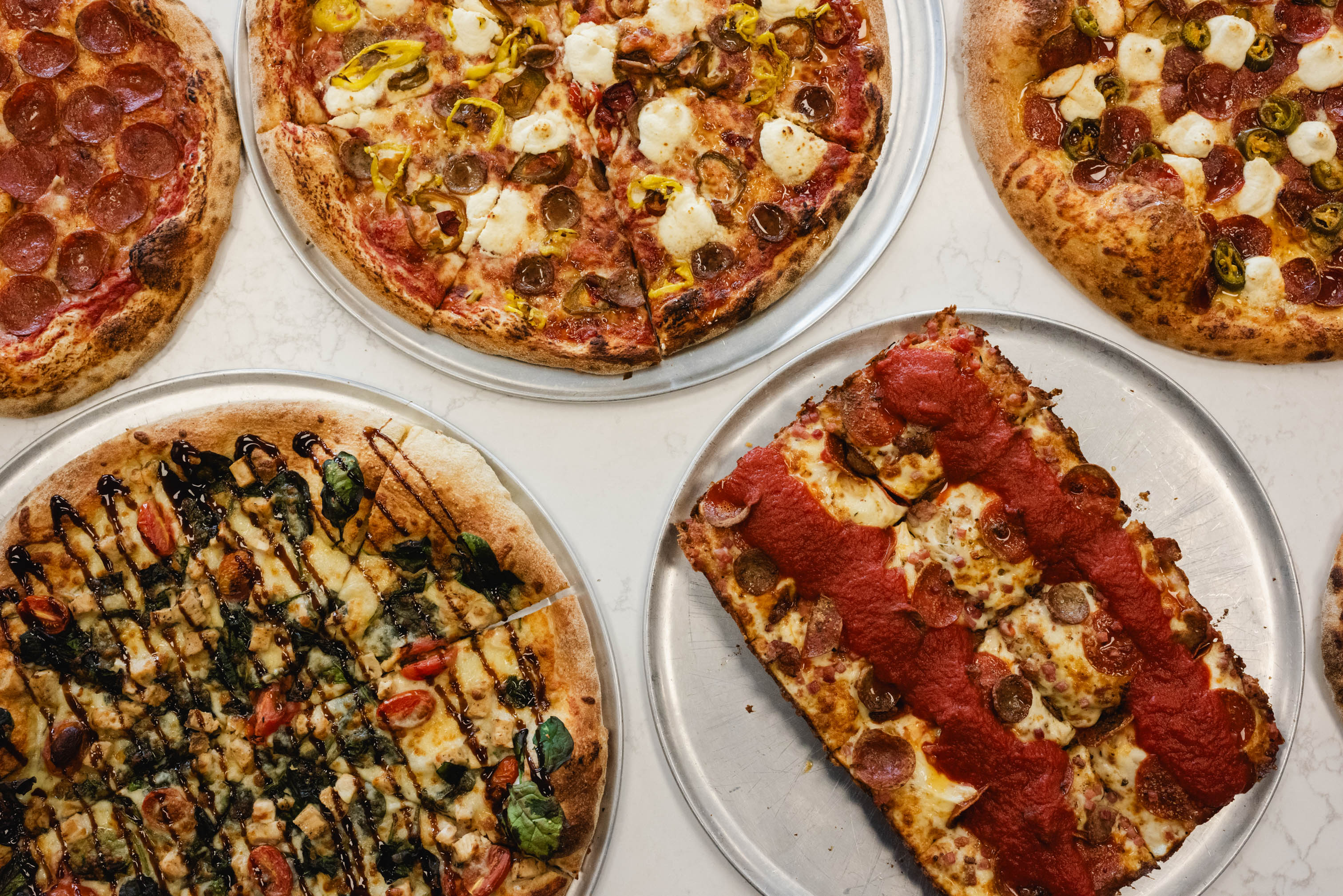 Assorted pizzas served on trays with different toppings