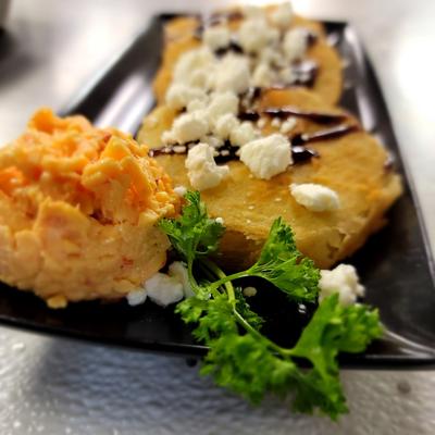 Fried fillet topped with cheese with scrambled egg on the side and cilantro garnish.