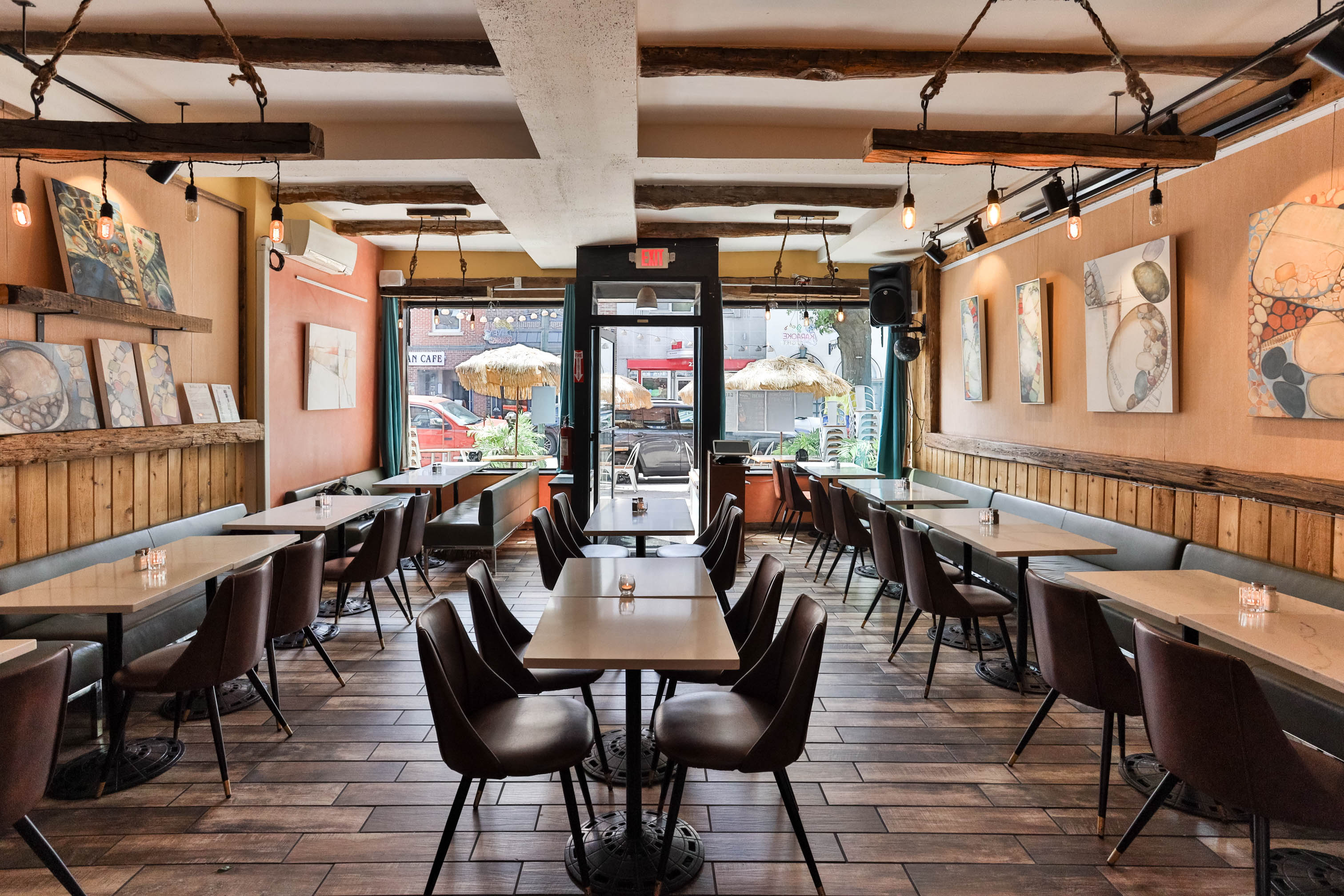 Interior featuring large windows, wooden tables, dark chairs, and exposed ceiling beams